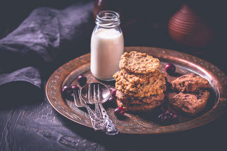 Homemade oatmeal cookies, cranberry cookies and bottle of milk on wooden tableの写真素材