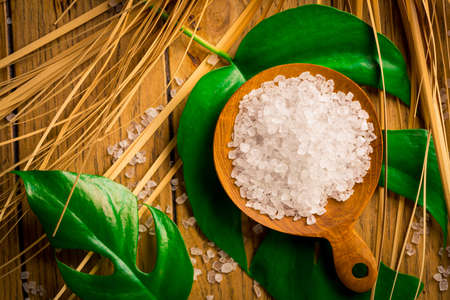 Spa salt with green leaf on wooden table. Healthy relaxation, therapy and treatment. Alternative lifestyle. Relax in bath.の写真素材