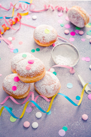 Traditional Berliner for carnival and party. German Krapfen or donuts with streamers and confetti. Colorful carnival or birthday imageの写真素材
