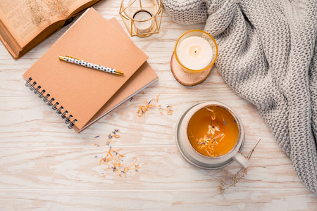 Hot herbal tea with notepad, candle, book and blanket. Cozy and hygge lifestyleの写真素材