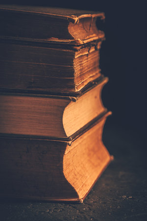 Stack of antique leather bound books against dark backgroundの写真素材