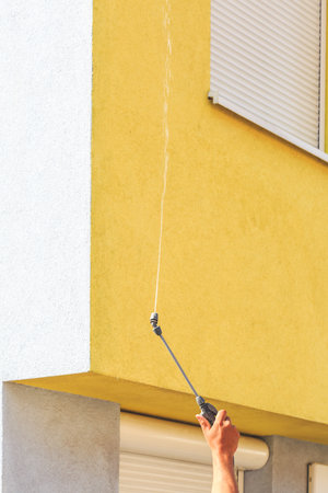 Applying cleaning supplies on dirty facade with high-pressure water blasterの写真素材