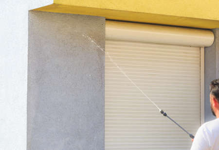 Applying cleaning supplies on dirty facade with high-pressure water blasterの写真素材