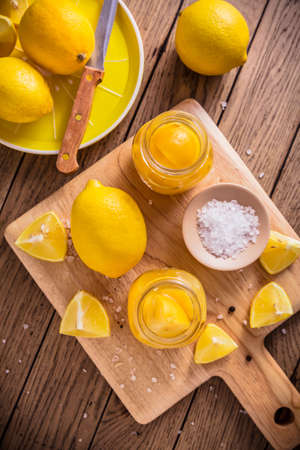 Preserved, salted canned lemons, lemon pickle on wooden background. Moroccan cuisineの写真素材