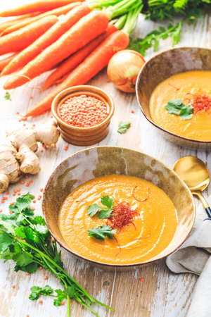 Homemade red lentil soup with carrots, ginger and coconut milk with ingredientsの写真素材