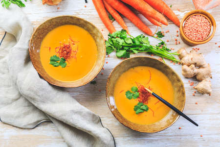 Homemade red lentil soup with carrots, ginger and coconut milk with ingredientsの写真素材