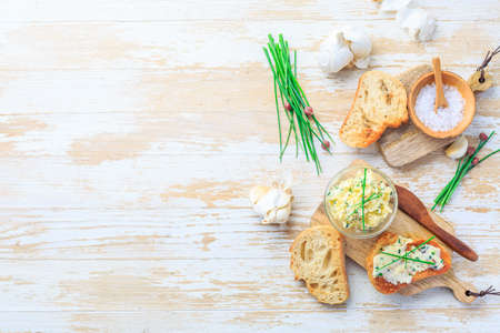 Homemade garlic butter with herbs and chives and fresh roasted baguette with salt and copy spaceの写真素材