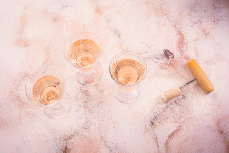 Three glasses of rose wine at wine tasting with bottle opener on pink marble background