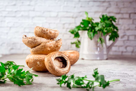 Raw portobello mushrooms with fresh parsley on kitchen table prepared for cookingの写真素材