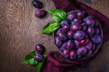 Fresh plums on plate over dark wooden backgroundの写真素材