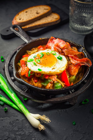 Letscho - tasty Hungarian vegetable stew with peppers, tomatoes  and onions, served with bacon and fried eggの写真素材