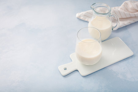 Buttermilk, kefir, yogurt with probiotics, ayran in glass and jar. Probiotic cold fermented dairy drink. Trendy food and drink.の写真素材