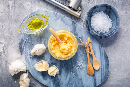 Homemade garlic paste in a jar with peeled garlic, salt, crusher and garlic heads.の写真素材