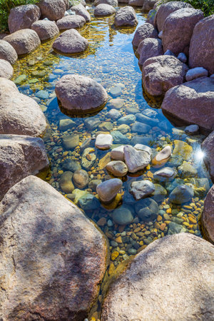Small pond in a garden as landscaping design element with rock, pebbles and gravelの写真素材