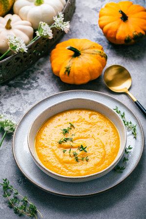 Pumpkin soup with pumpkin seeds served in bowl on rustic kitchen tableの写真素材