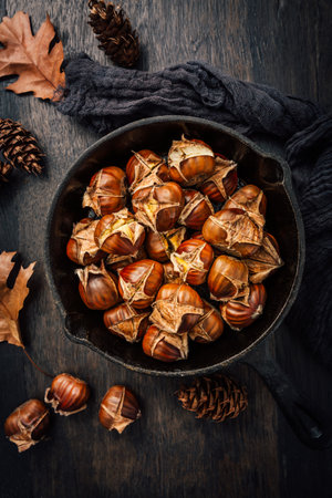 Roasted chestnuts in iron pan on old kitchen tableの写真素材