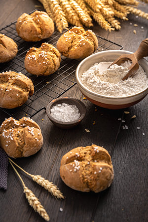 Homemade spelt bread buns with salt on wooden background