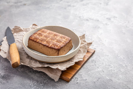Organic smoked tofu on kitchen table with knifeの写真素材