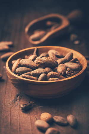 Organic cocoa beans in wooden bowl on wooden backgroundの写真素材