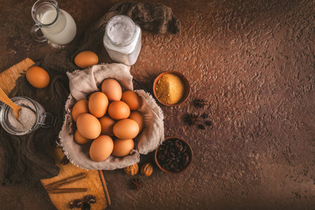 Organic brown eggs with assorted baking ingredients and kitchen utensils in brown toneの写真素材