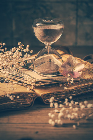 Hourglass with old book. Symbol of passing time and memories. Conceptual vintage imageの写真素材