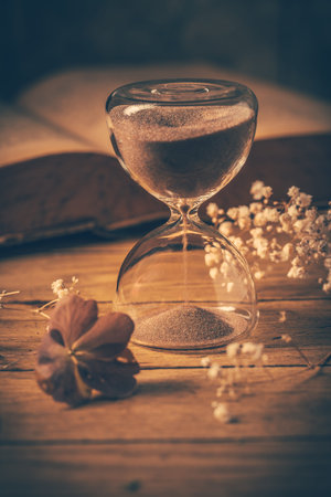 Hourglass with old book. Symbol of passing time and memories. Conceptual vintage image