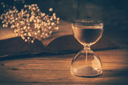 Hourglass with old book. Symbol of passing time and memories. Conceptual vintage image