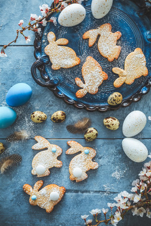 Homemade almond bunny cookies for Easter with Easter eggs in blue tone