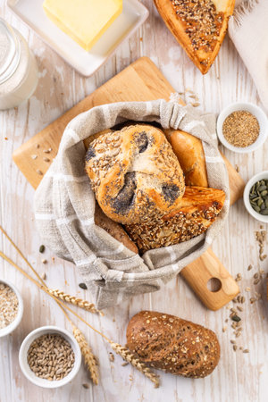 Variation of bread rolls or buns in breadbag with butter and assorted seeds