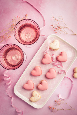 Happy Mothers Day, Happy Valentine - sweet macarons in heart shape and glasses of rose sparkling wine in pink toneの写真素材