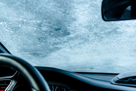 Frozen car windshield covered with ice and snow on a winter day. Selective focus.の写真素材
