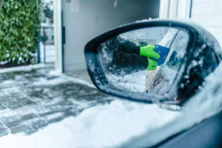 Teenager  cleans car after a snowfall, removing snow and scraping iceの写真素材