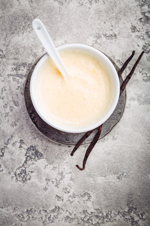 Homemade vanilla sauce in small bowl on grey backgroundの写真素材