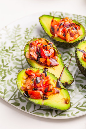Vegan appetizers, avocados filled with bruschetta and balsamic vinaigrette