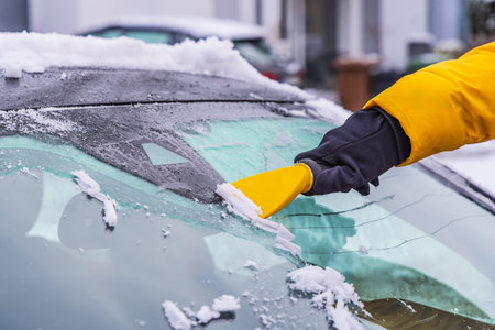Removing snow and ice from car windshield. Clean car window in winter from snow.