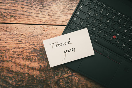 Closeup of Thank You sticky note message on laptop on wooden backgroundの写真素材