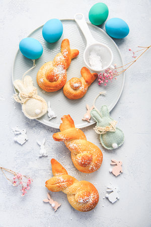 Easter baking - Buns made from yeast dough in a shape of Easter bunny and colored eggsの写真素材