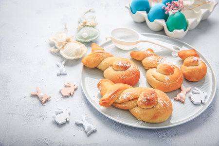 Easter baking - Buns made from yeast dough in a shape of Easter bunny and colored eggsの写真素材