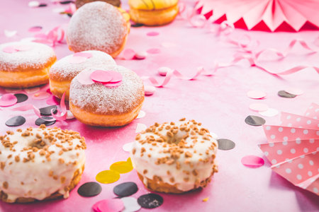 Traditional Berliner for carnival and party. German Krapfen or donuts with streamers and confetti. Colorful carnival or birthday imageの写真素材