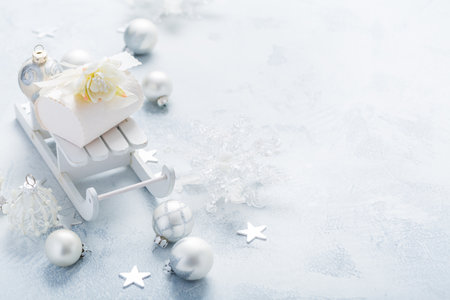 Christmas ornaments, balls and small present box on sledge in silver and snowy whiteの写真素材