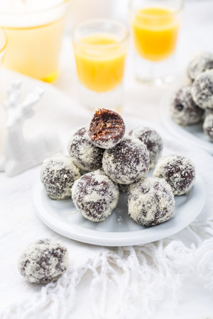 Energy balls for Christmas. Healthy raw vegan dessert (bliss balls), vegetarian truffles, sugar free candies made of dates, almond, cocoa powder and cranberries with eggnogの写真素材