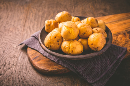 Boiled young potatoes in bowl on cutting boardの写真素材