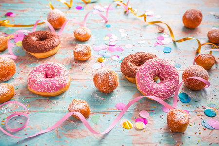 Traditional Berliner for carnival and party. German Krapfen or donuts with streamers and confetti. Colorful carnival or birthday imageの写真素材