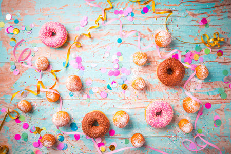 Traditional Berliner for carnival and party. German Krapfen or donuts with streamers and confetti. Colorful carnival or birthday imageの写真素材