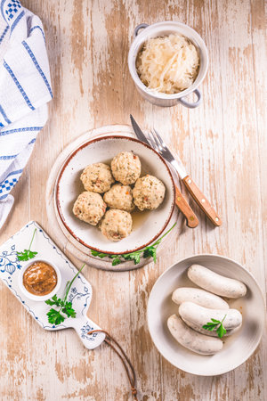 Traditional Bavarian cuisine - White veal sausage (Weisswurst) with pickled white cabbage (Sauerkraut) and bread dumplings with  Mustard Sauceの写真素材