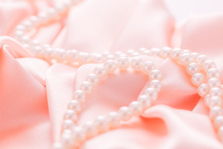 Pearl necklace on pink satin fabric. Wedding concept. Soft focusの写真素材
