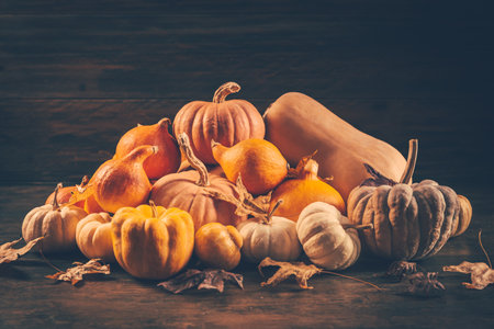 Assortment of pumpkins with autumn leaves on wooden backgroundの写真素材