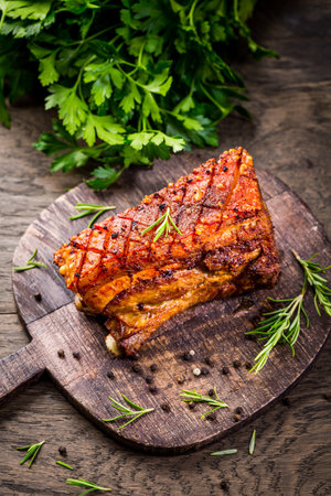 Roasted pork belly with crust and herbs on cutting boardの写真素材