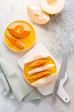 Fresh cantaloupe and lemon drop melon on cutting board - low calorie refreshment for hot summerの写真素材