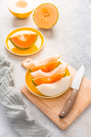 Fresh cantaloupe and lemon drop melon on cutting board - low calorie refreshment for hot summerの写真素材